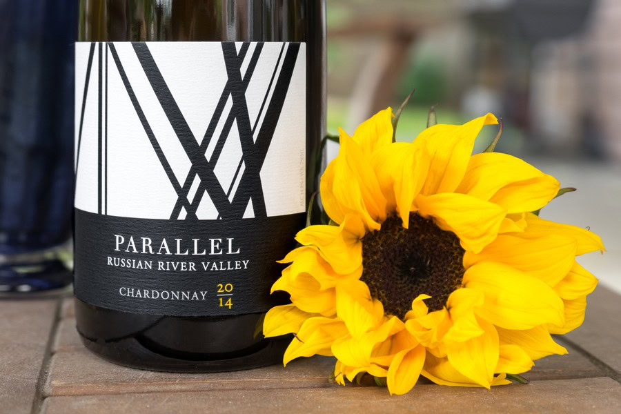 Parallel Wines Chardonnay 2014 bottle with sunflower on wooden surface.