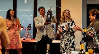 Group of people celebrating with wine bottles at a social event, promoting Parallel Wines.