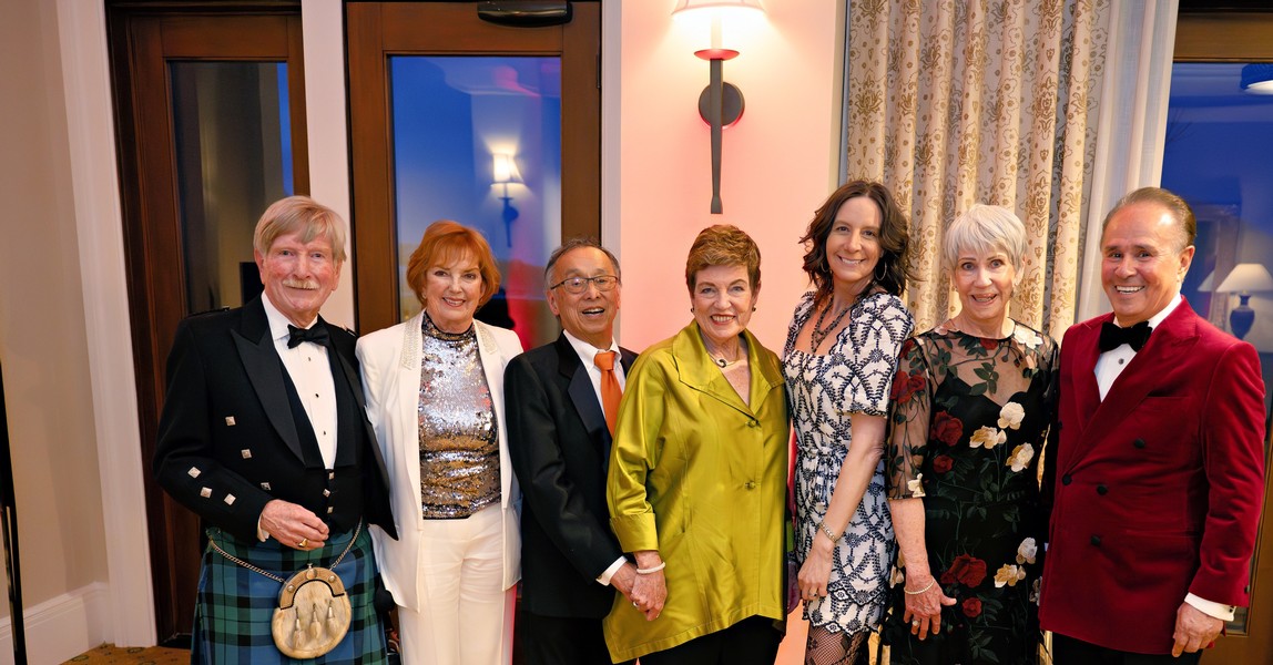 Group of elegantly dressed people at a formal event, celebrating with smiles.